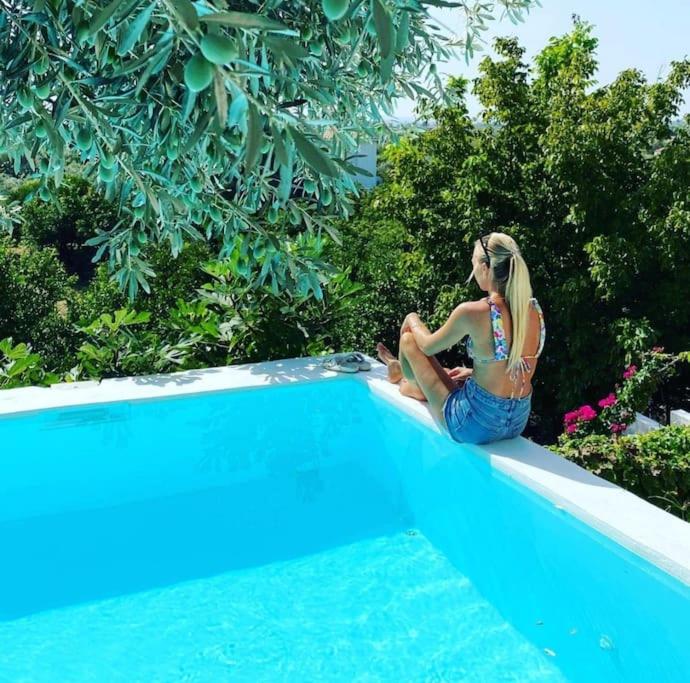 una donna seduta sul bordo di una piscina di Greek Island Guest House Samos Island a Samos