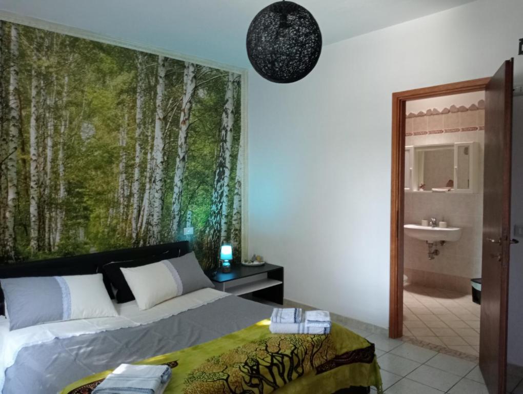1 dormitorio con 1 cama y un mural de árboles en la pared en La Mimosa, en Porto Garibaldi