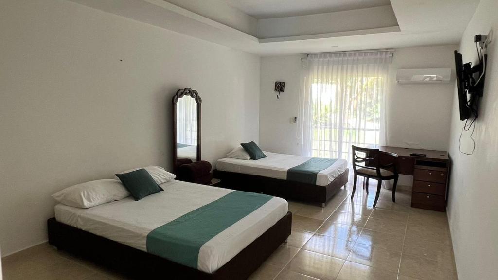 1 Schlafzimmer mit 2 Betten, einem Schreibtisch und einem Spiegel in der Unterkunft Aw Hotel Acawa Resort & Piscina in Armenia
