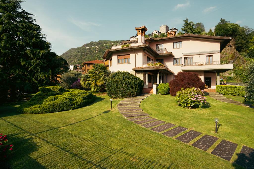 a house on a hill with a green lawn at Villa Dervio in Dervio