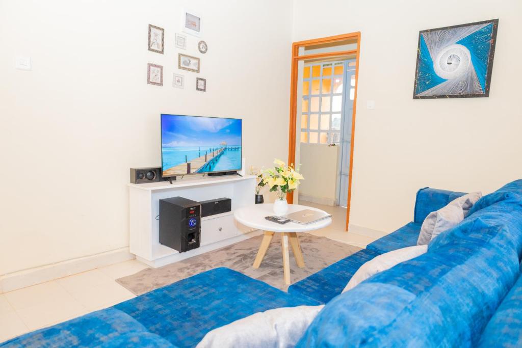 ein Wohnzimmer mit einem blauen Sofa und einem TV in der Unterkunft The Stay Comfort in Nyeri