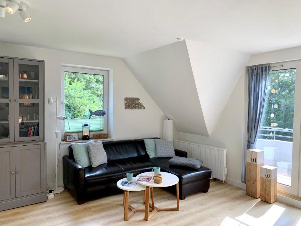 ein Wohnzimmer mit einer schwarzen Ledercouch und einem Tisch in der Unterkunft FeWo FriesenSPOt in Sankt Peter-Ording