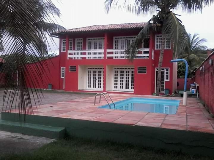 un edificio rojo con piscina frente a una casa en Casa em Porto Seguro, en Porto Seguro