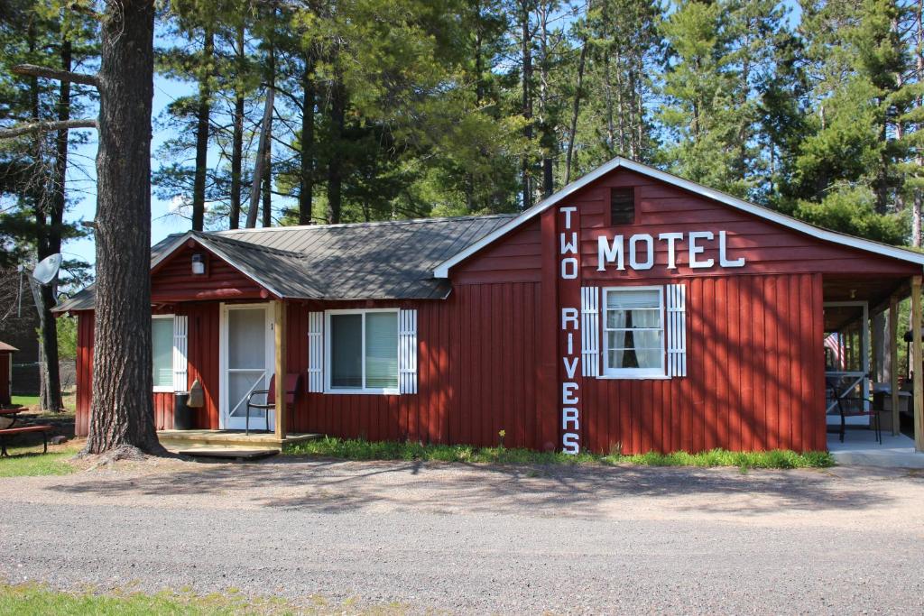una cabaña roja con un letrero en el costado. en Two Rivers Motel and Cabins, 