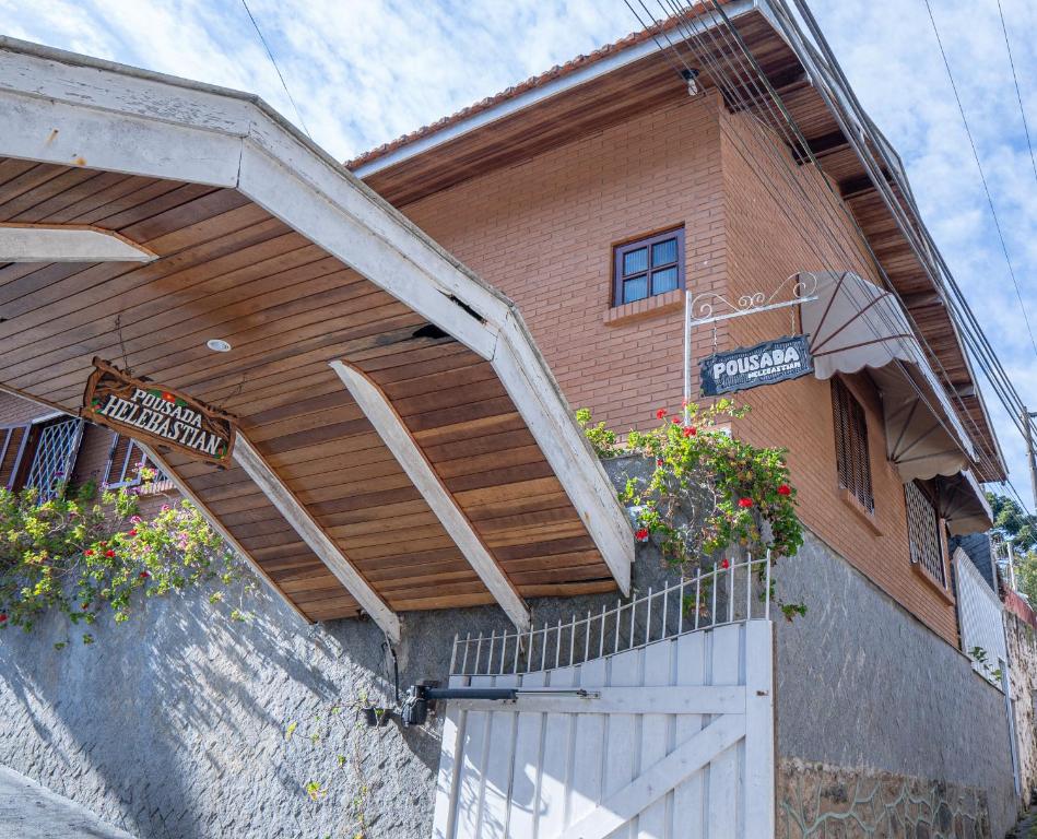 a house with a porch with flowers on it at pousada helebastian in Campos do Jordão