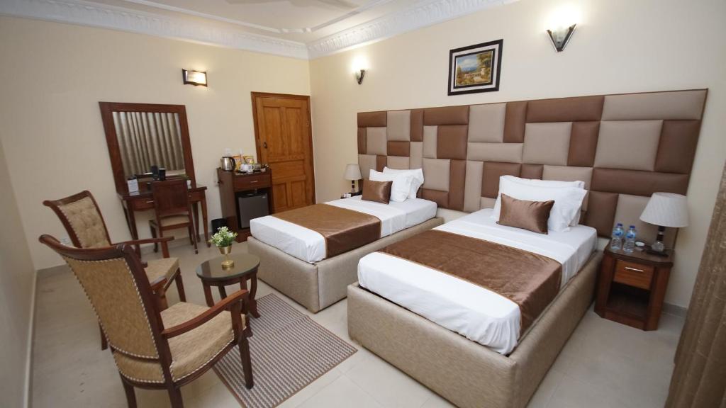a hotel room with two beds and a chair at World Inn Karachi in Karachi