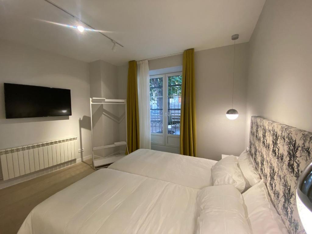 1 dormitorio con cama blanca y ventana en APARTAMENTOS LA FLORA BURGOS todos con aire acondicionado y ascensor, en Burgos