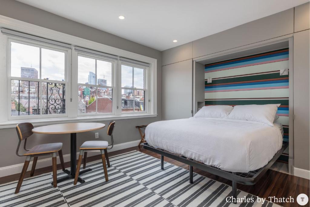 1 dormitorio con cama, mesa y ventanas en 94 Charles Street by Thatch en Boston