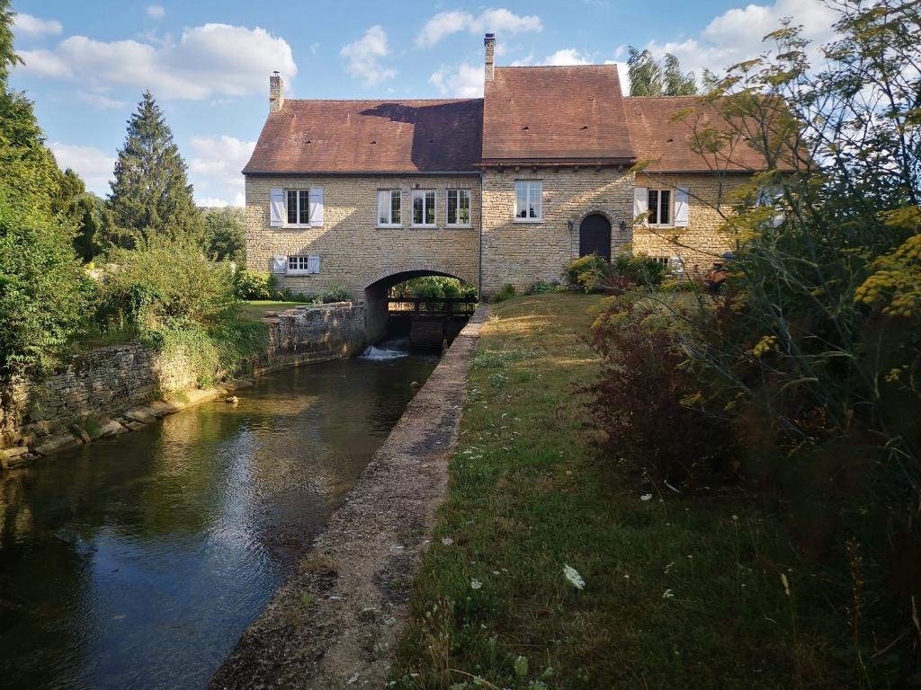 a building with a bridge next to a river at Le Moulin de Villiers in Gudmont