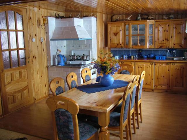 a kitchen with a wooden table with chairs and a kitchen with a stove at Eko-Sen in Białowieża
