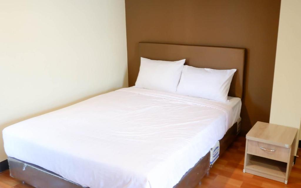 a bed in a small room with white sheets and pillows at Airport A1 Hotel in Chiang Mai