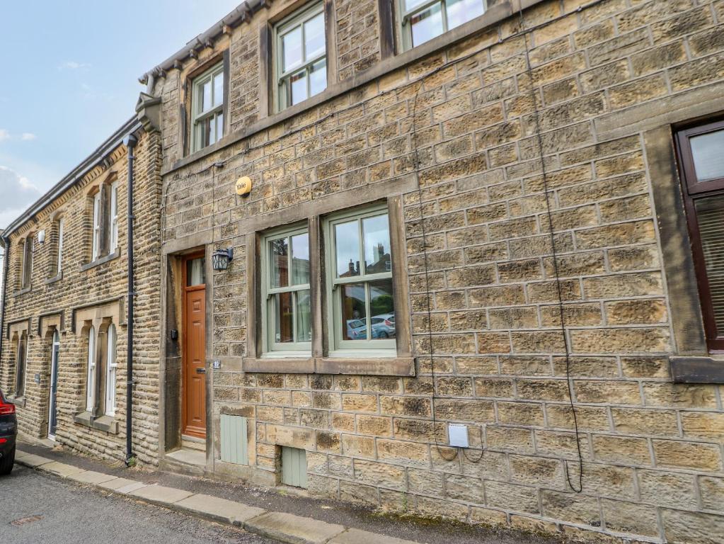 a brick building with a door and windows at 19 The Village in Holmfirth