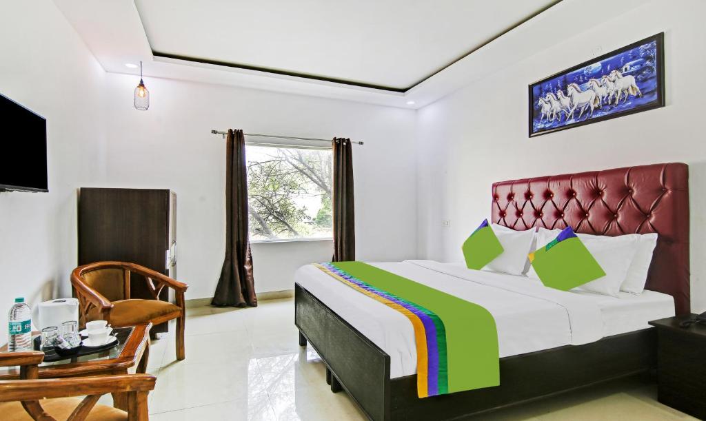 a bedroom with a bed and a chair and a television at Treebo Trend Royal Empire in Chandīgarh