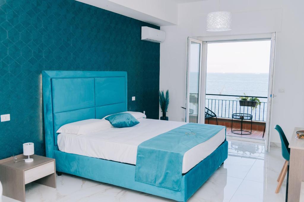 una camera da letto con un letto blu e un balcone di FronteMare Suite a Castellammare di Stabia