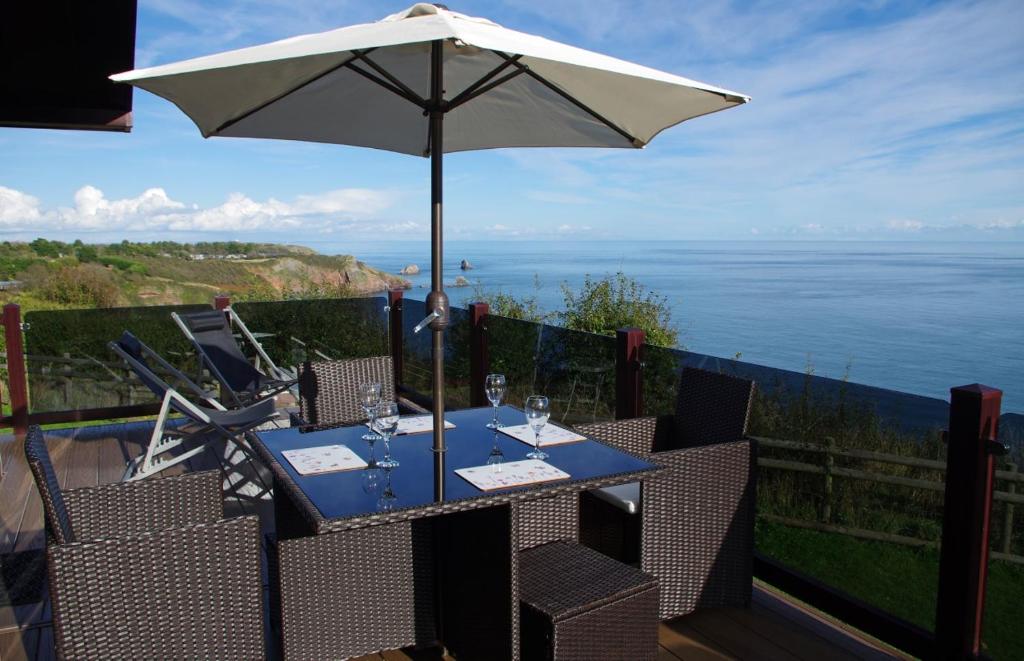 a table with an umbrella and chairs and the ocean at Sea View Lodge in Brixham