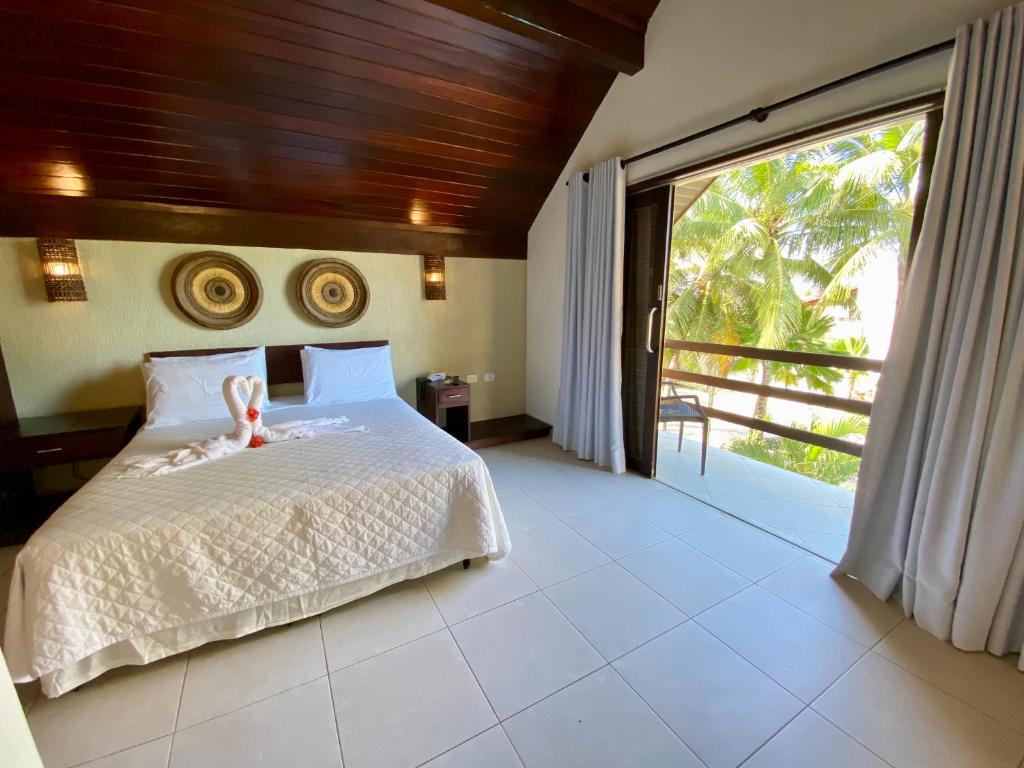 a bedroom with a white bed and a large window at Pousada Pérola do Porto in Porto De Galinhas