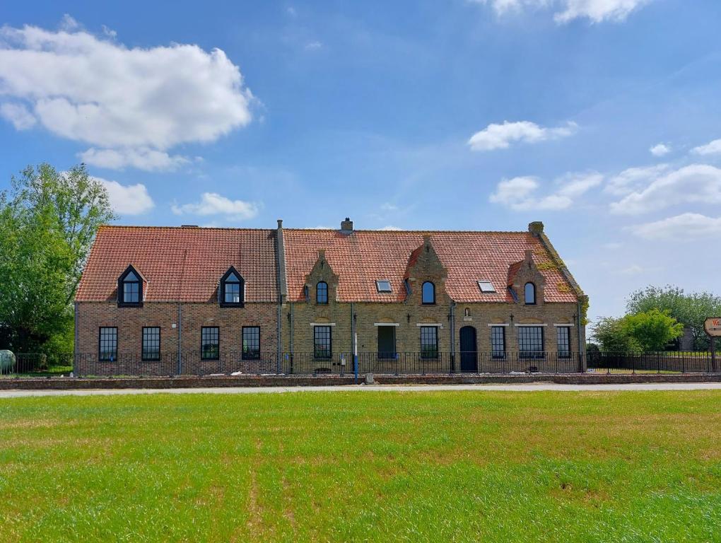 a large brick building with a grass field in front of it at Vakantiehoeve Walleboom in Lo-Reninge