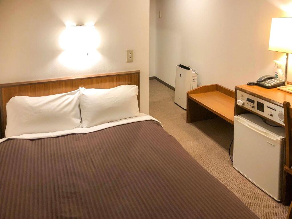 a hotel room with a bed and a desk with a phone at City Hotel Air Port in Prince - Vacation STAY 80750v in Izumi-Sano