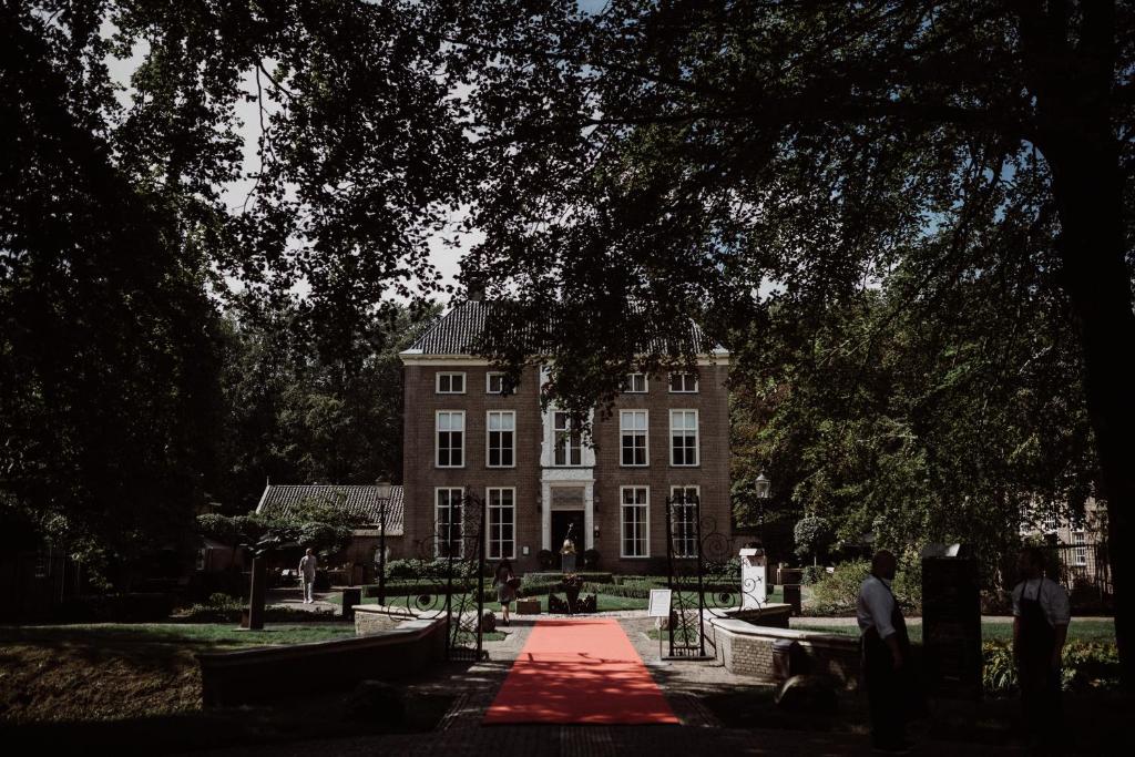 un gran edificio con un camino rojo delante de él en Châteauhotel De Havixhorst en Schiphorst