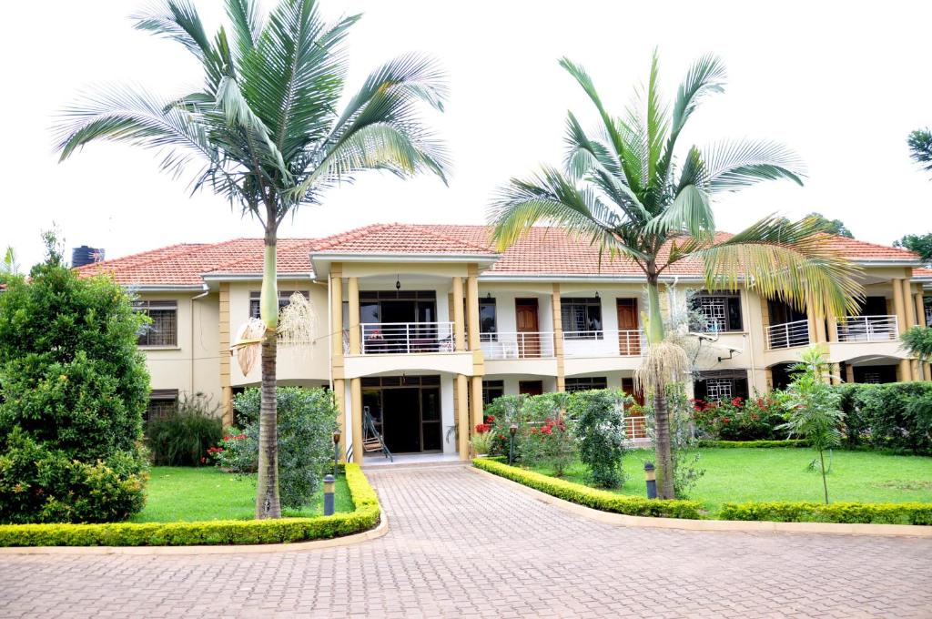 a large house with palm trees in front of it at Olive Gardens Hotel Kampala in Kampala