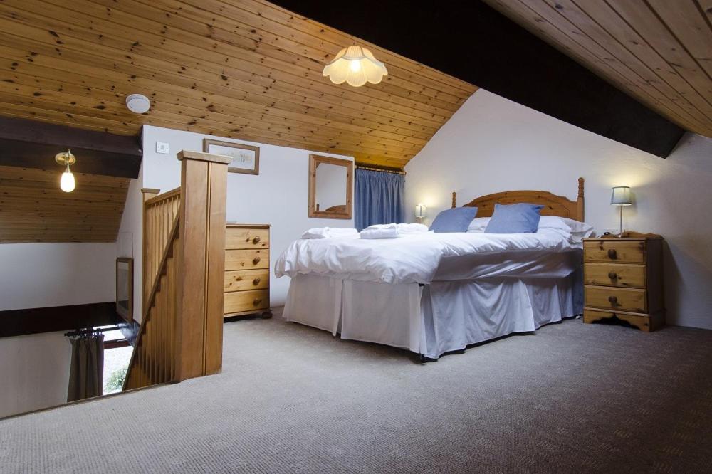 um quarto com 2 camas e um tecto de madeira em Hafoty Farm Cottages em Caernarfon