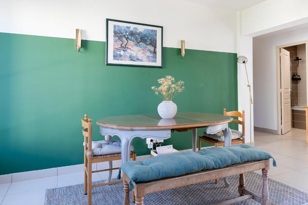 ein Esszimmer mit einem Tisch und einer grünen Wand in der Unterkunft Appartement spacieux 1 chambre parking gratuit in Valence