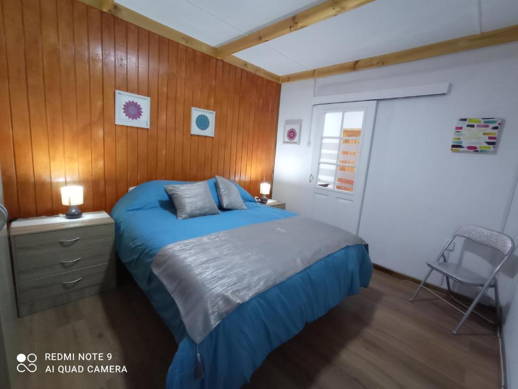 a bedroom with a blue bed and a wooden wall at Loft Tongoy Peninsula sin estacionamiento in Coquimbo