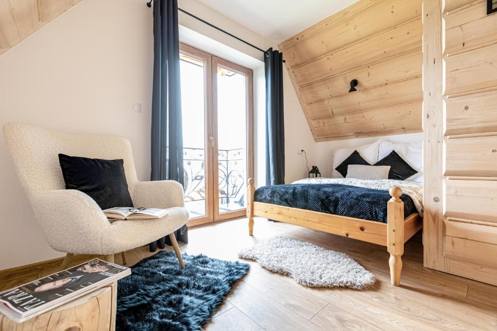 a bedroom with a bed and a chair and a window at Cyrhlański Wypas in Zakopane