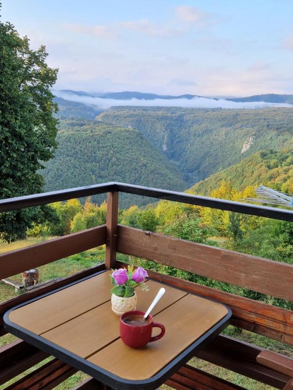 a table with a coffee cup and flowers on a balcony at Guesthouse Loncar in Plitvička Jezera