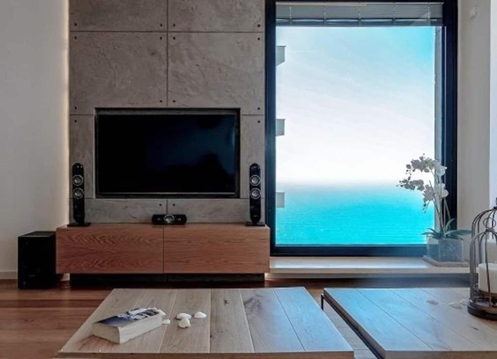 a living room with a tv and a large window at Ocean View in Bat Yam