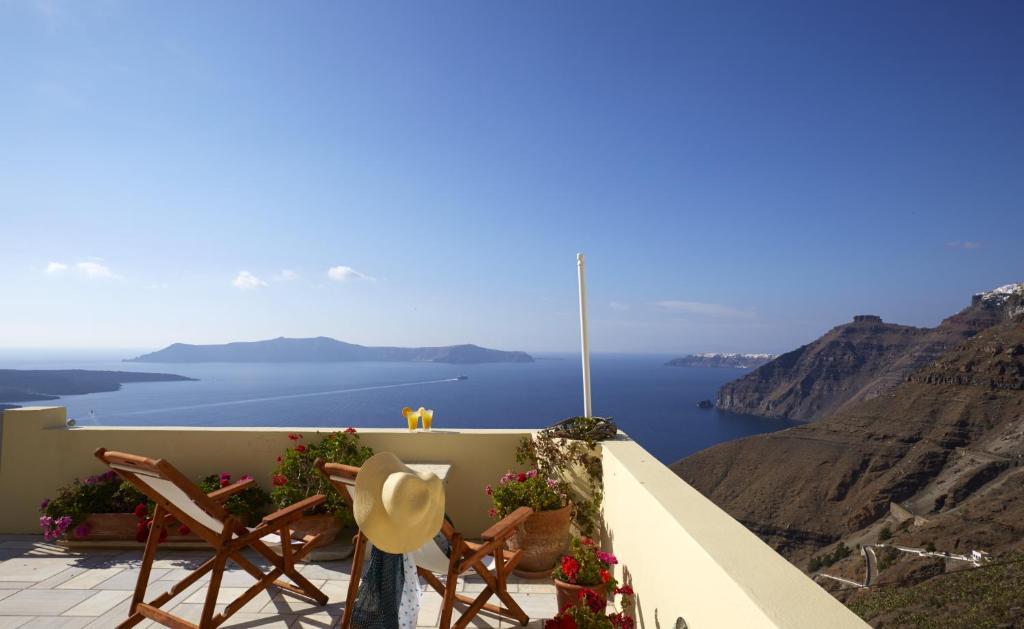 a balcony with chairs and a view of the ocean at Cori Rigas Suites in Fira