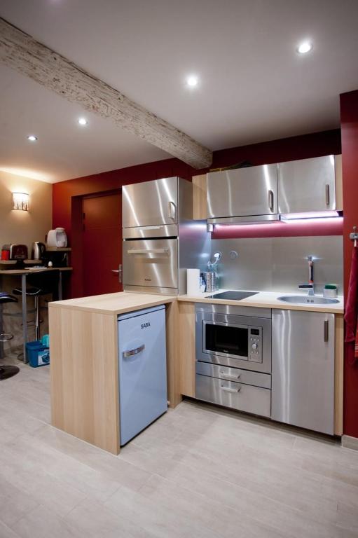 a large kitchen with stainless steel appliances and red walls at Very Nice Studio Ideal For 2 Near The Halles in Avignon