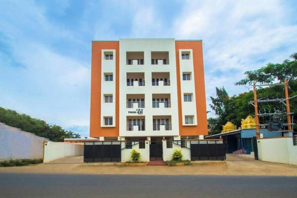 a large white and orange building on the side of a street at ThulasiRams Service Apartments in Coimbatore