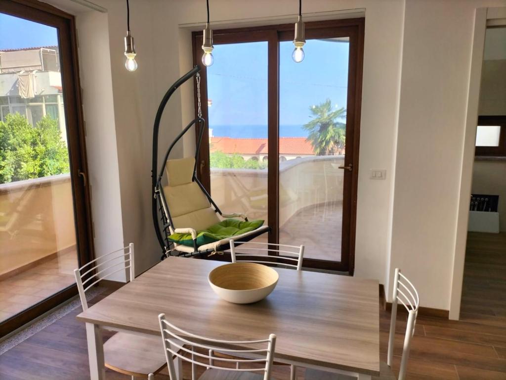 a dining room with a table and chairs and a large window at Appartamenti MiNuMa Tropea in Tropea