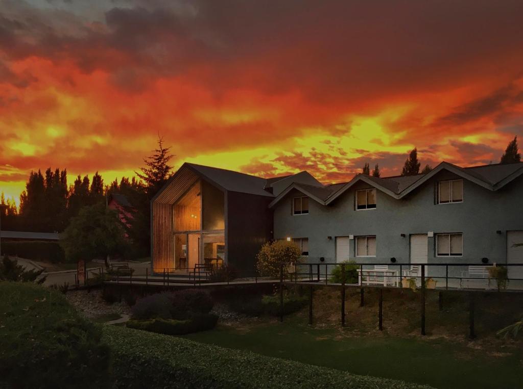 a house with a sunset in the background at Apart Hotel Jardín in El Calafate