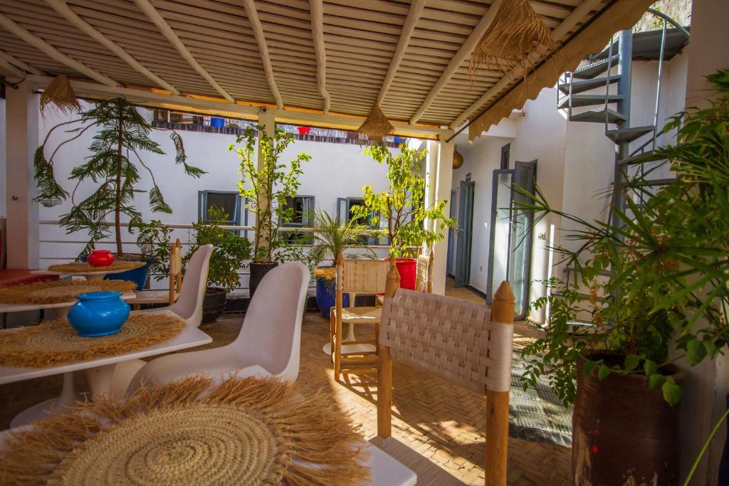 un patio con mesas, sillas y macetas en Riad Les Jardins des Lilas, en Marrakech