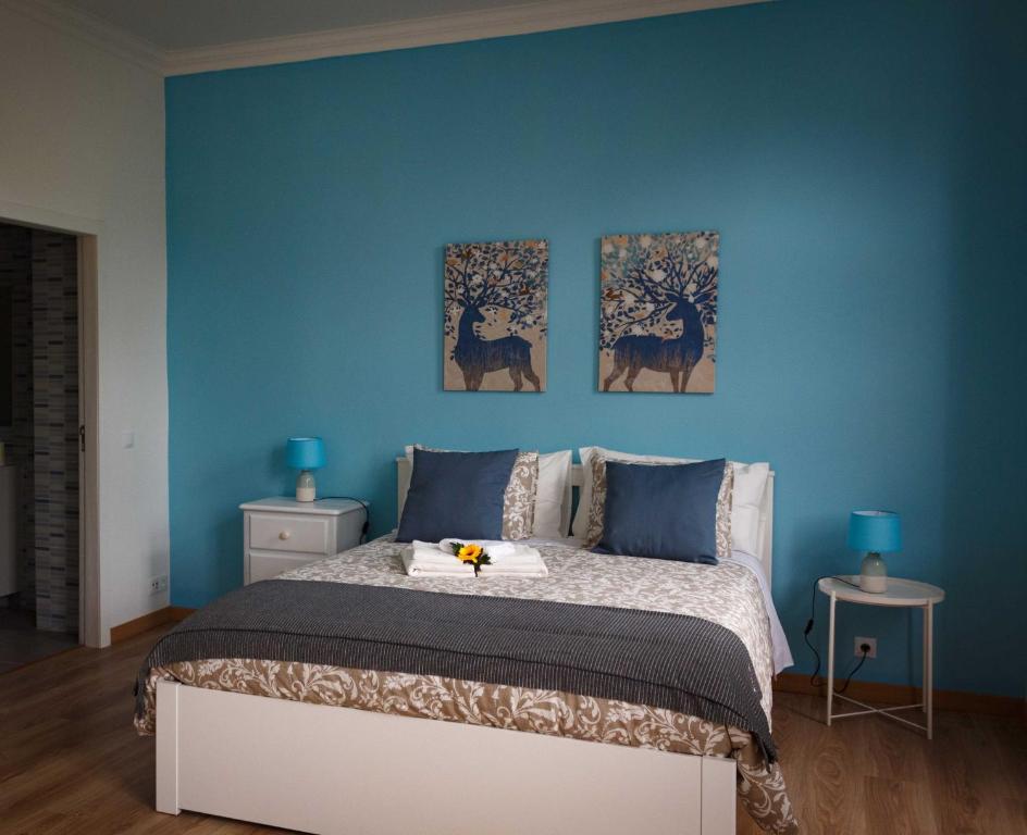a blue bedroom with a bed and three paintings on the wall at Flor&Fidalgo Guest House in Sintra