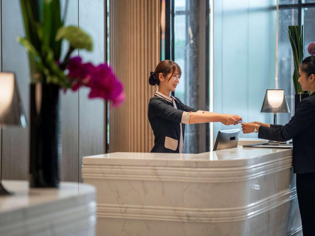 a woman shaking hands with a man at a desk at Pullman Suzhou Zhonghui in Suzhou