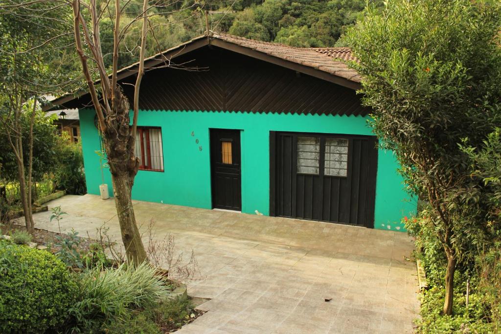una casa verde con puerta negra y entrada en Casa Mendes en Gramado