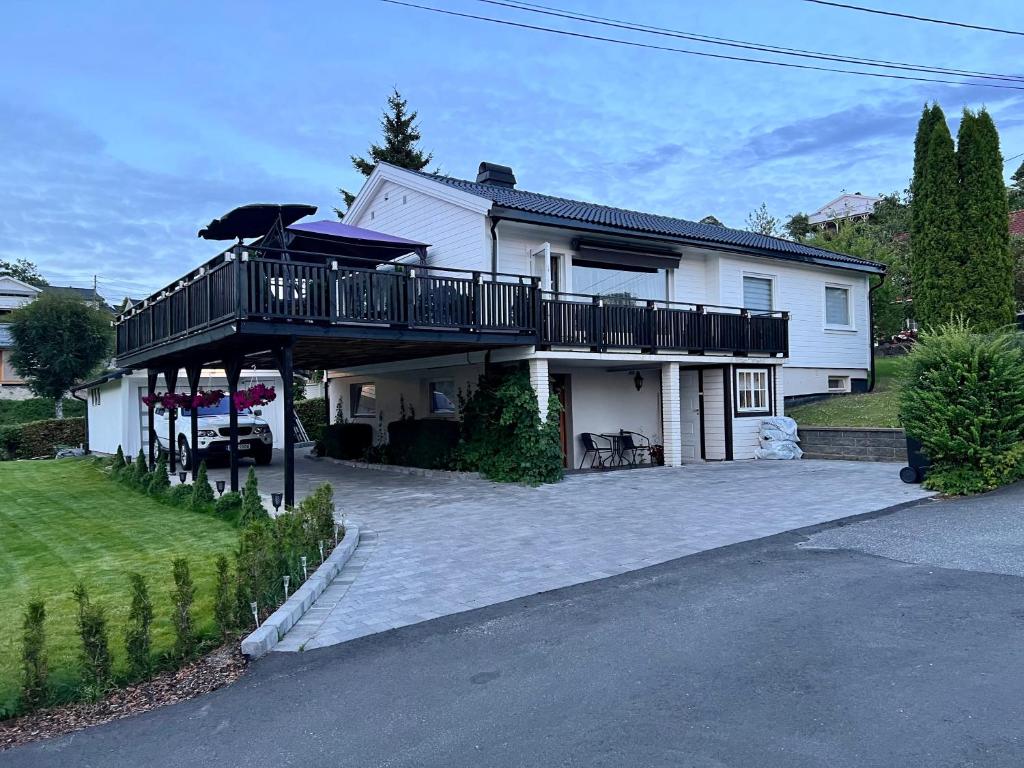 Cette grande maison blanche dispose d'un balcon et d'une allée. dans l'établissement koselig leilighet nær EB stranda, à Arendal
