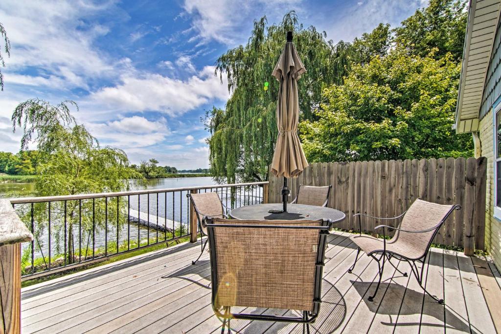 um deque com uma mesa, cadeiras e um guarda-sol em Charming Horicon Cottage and Dock on Rock River em Juneau