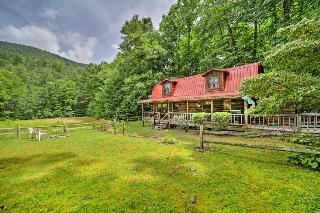 a house with a red roof in the middle of a field at Scenic Creekside Cabin with Wraparound Porch! in Highlands