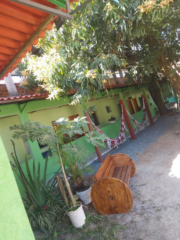 a wooden bench next to a building with trees at Pousada Tropical in Aparecida