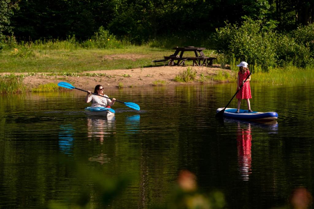 dos personas en kayaks en un río con una mujer en La Bohémienne des yourtes du petit ruisseau, en Mandeville
