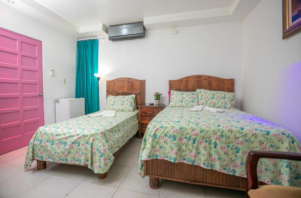 1 dormitorio con 2 camas y puerta rosa en Casa de Huespedes Colonial en Santo Domingo