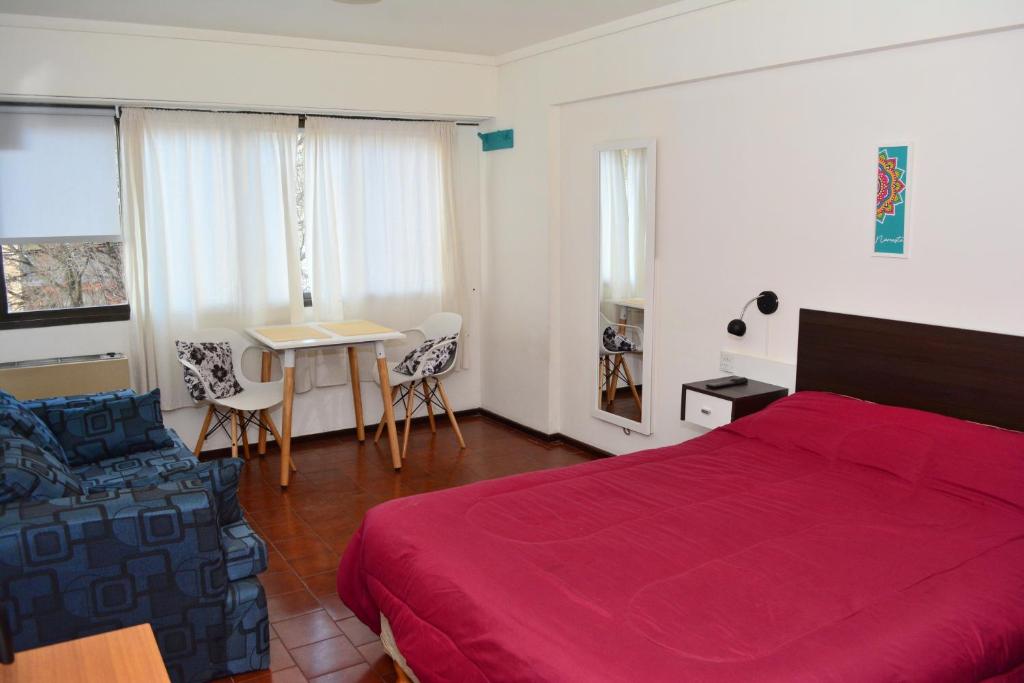 - une chambre avec un lit rouge, une table et des chaises dans l'établissement Orillas del Nahuel, à San Carlos de Bariloche