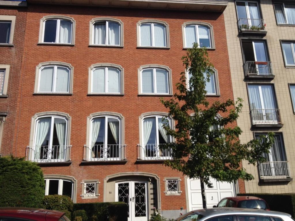 un edificio de ladrillo con ventanas y balcones blancos en B&B Capitaine Piret en Bruselas