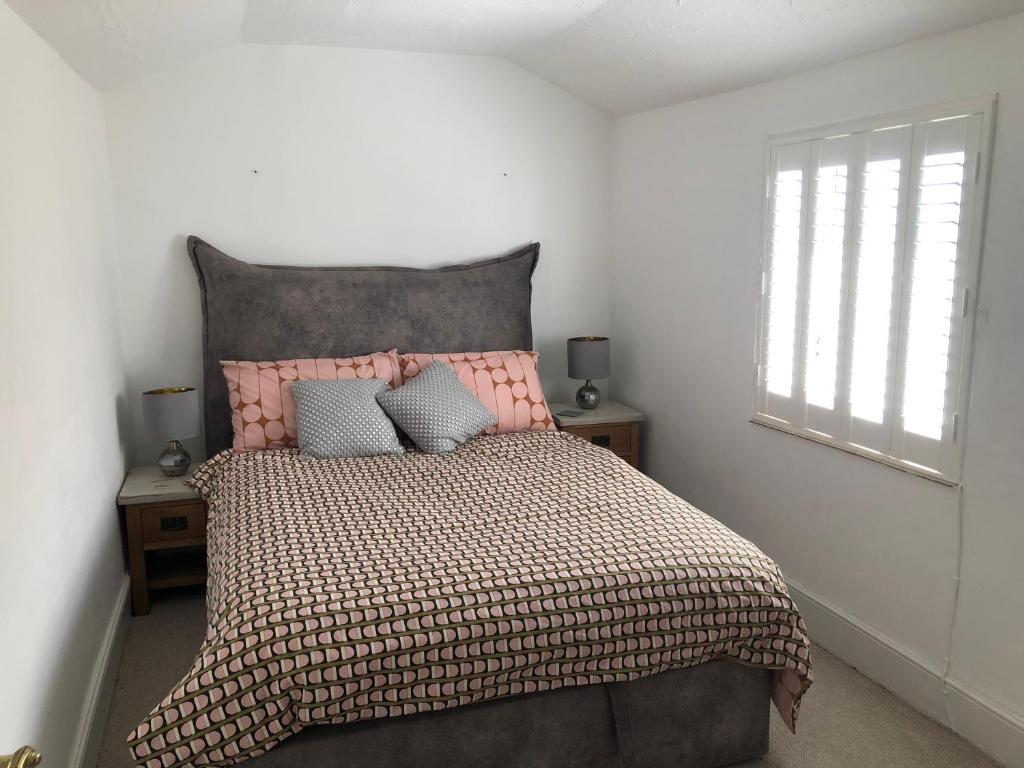 a bedroom with a bed with a pink headboard and a window at Homely Victorian Terraced Town House with Parking. in Taunton