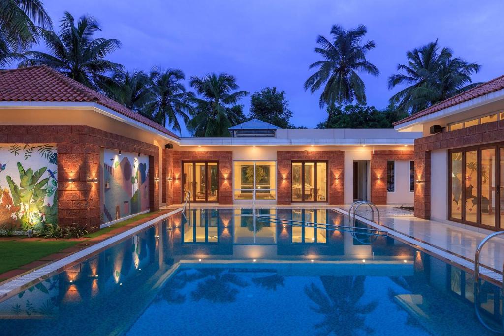 a villa with a swimming pool at night at Prism and Palette by StayVista - Nestled amidst greenery, offering vibrant interiors, a swimming pool, snooker table, gazebo, and a spacious lawn area in Alibaug