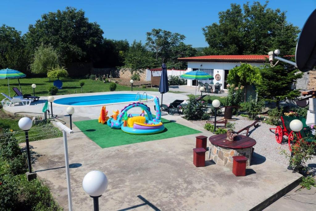 um quintal com uma piscina e um parque infantil em Nature House Bulgaria em Radanovo